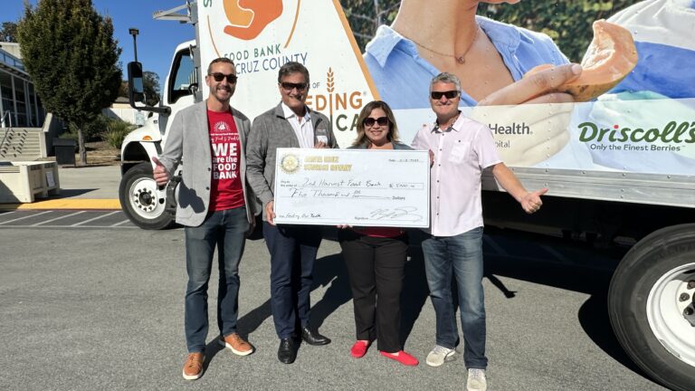 four people in front of food bank truck holding big check